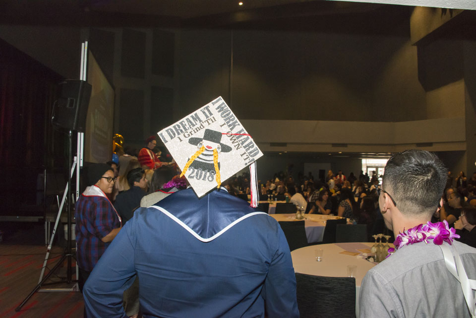 A student showing their decorated graduation cap with the inscription 