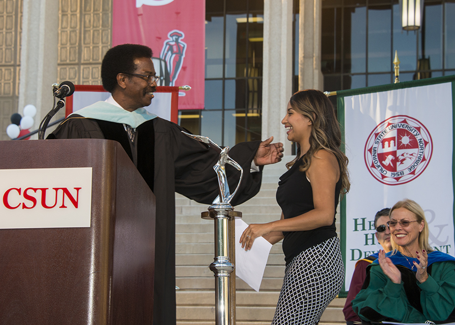 William Watkins greets Kenya Lopez at a podium in front of the Oviatt Library.
