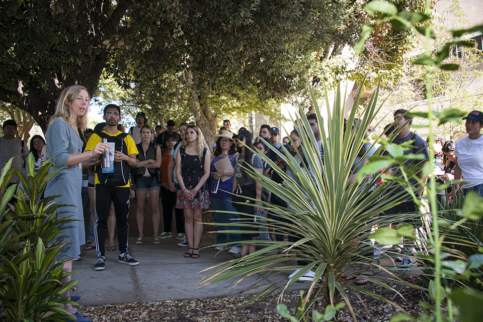 Erica Wohldmann tells a group of students and faculty about plants shows in the foreground.