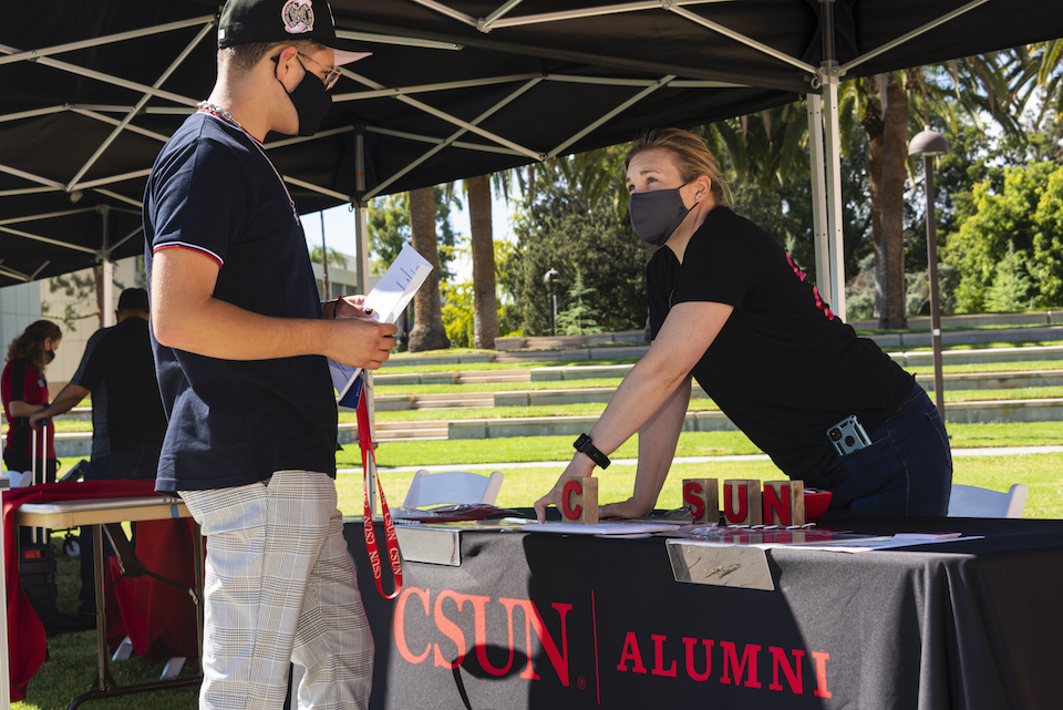 Student visits with staff at the CSUN Alumni booth.