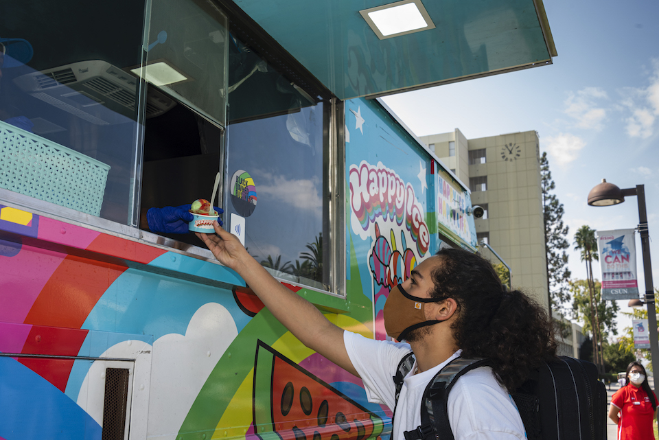 Student is handed frozen treat through the window of colorful truck.