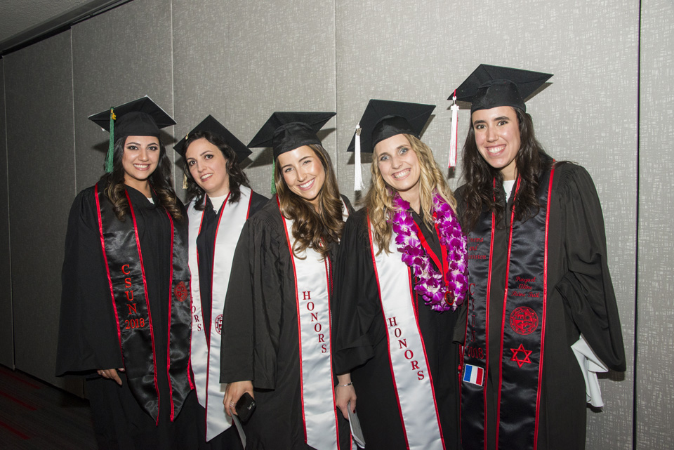Five smiling girls in cap and gown