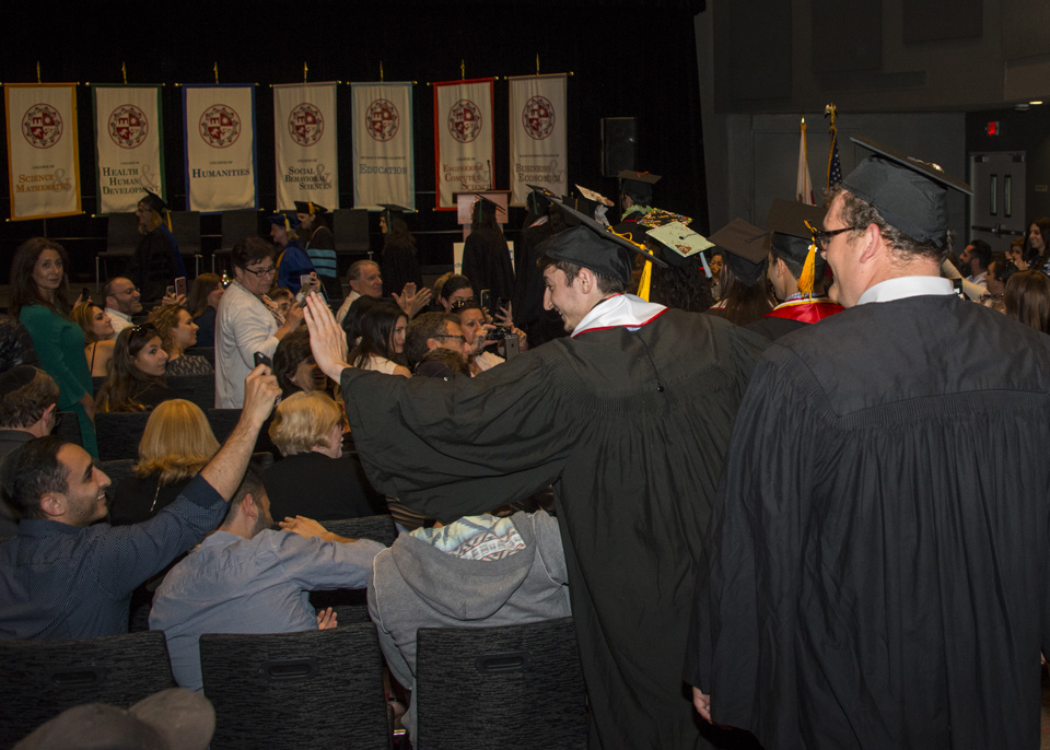 Graduating student high-fiving person in audience while walking down aisle