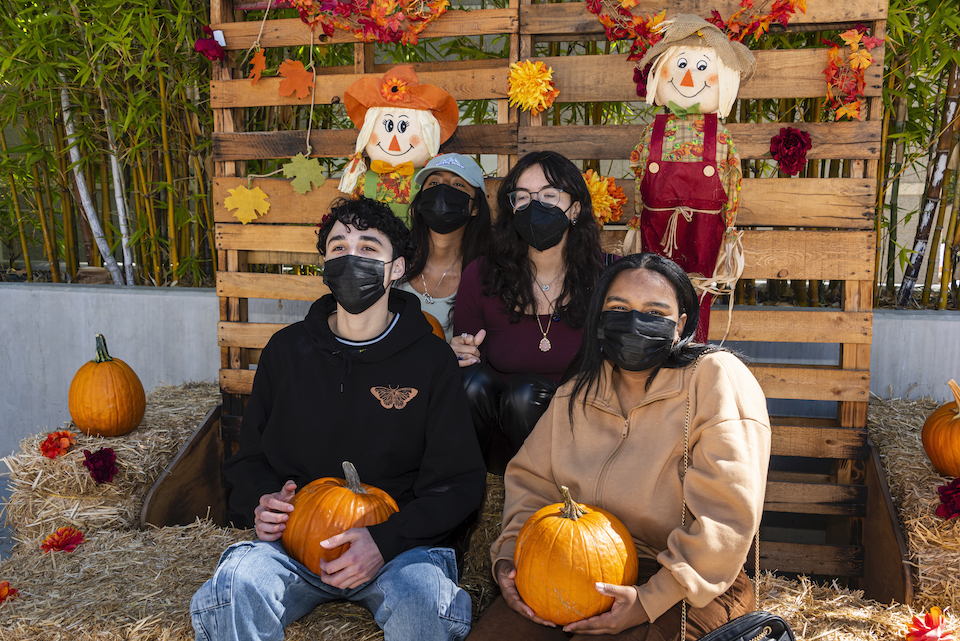 Four people wearing masks pose for photo in photo booth