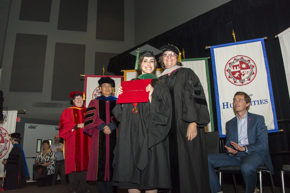Graduate smiling on stage holding diploma