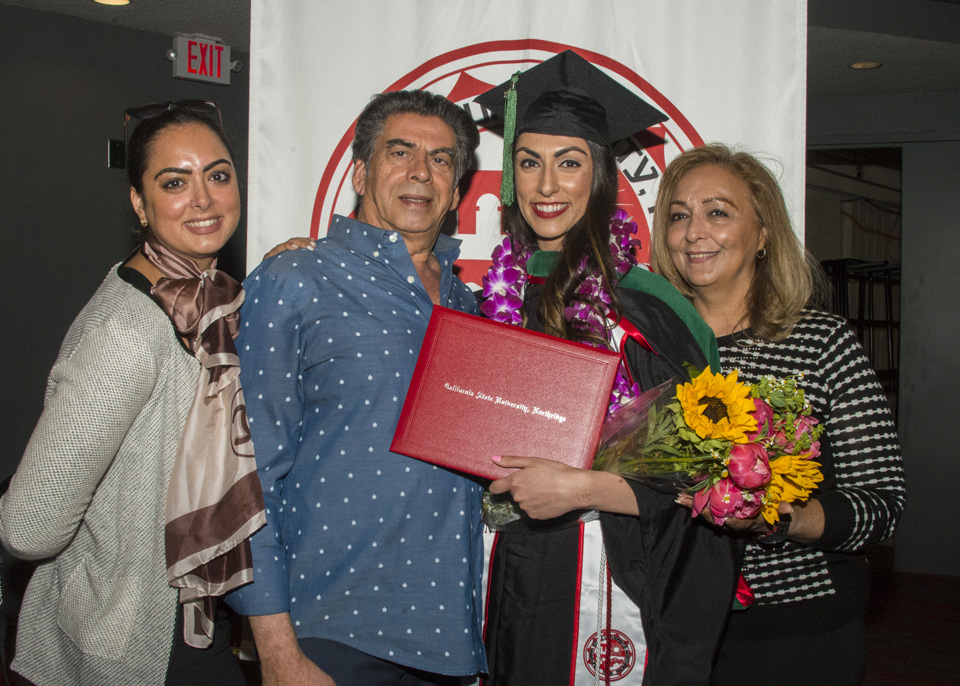 Graduate posing with diploma and family