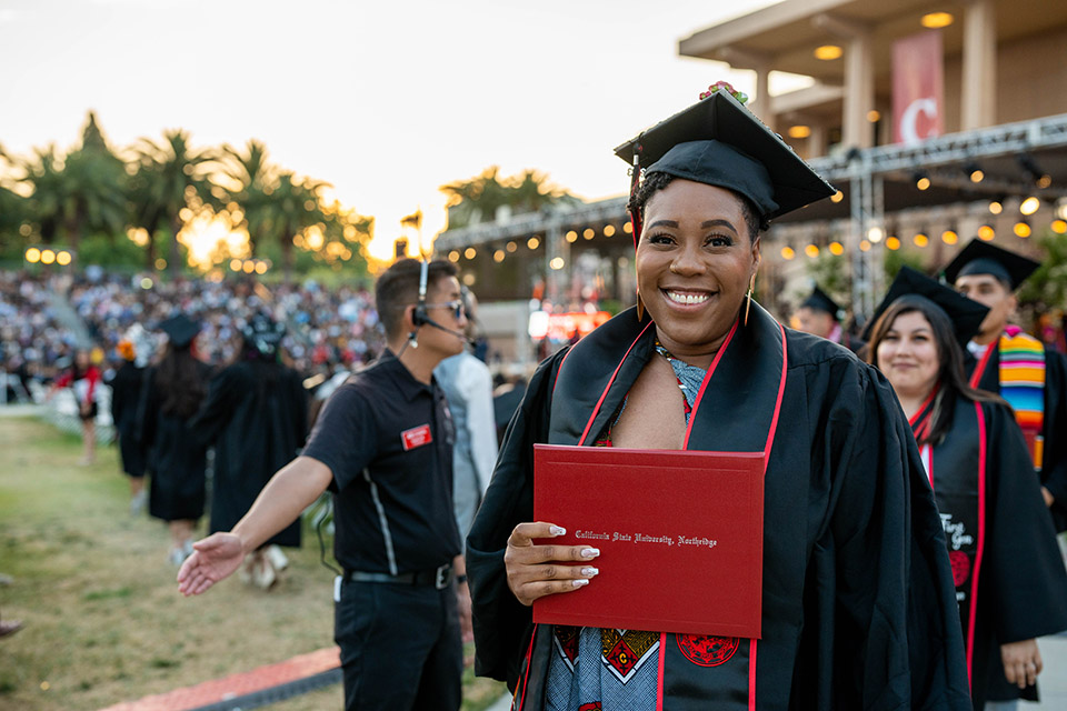 A student carries a diploma during the second commencement ceremony for the College of Health and Human Development on May 21, 2023.