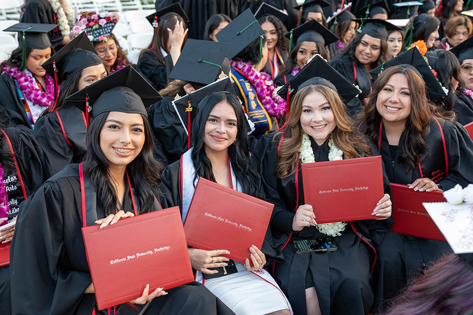 A group of students hold their diplomas during the second College of Health and Human Development ceremony on May 21, 2023.