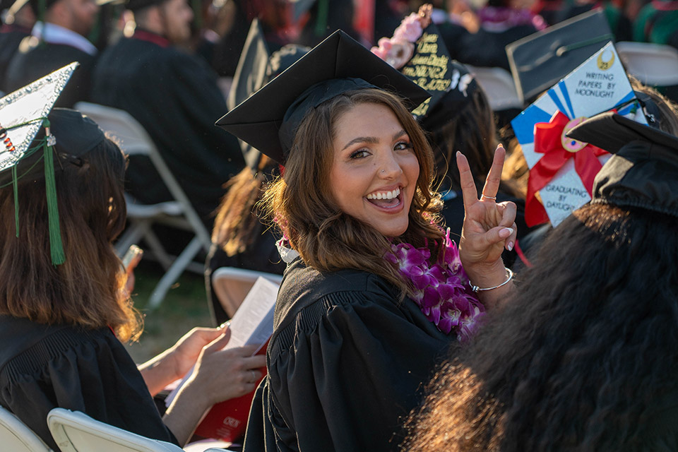 A student celebrates with a peace sign during the second College of Health and Human Development ceremony on May 21, 2023.