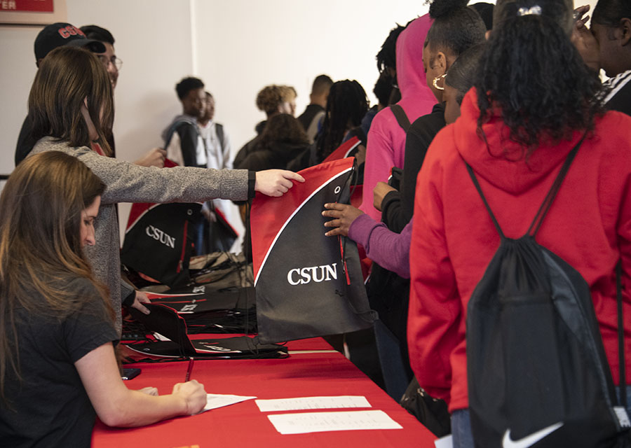 Students stand in line and grab their CSUN bag.