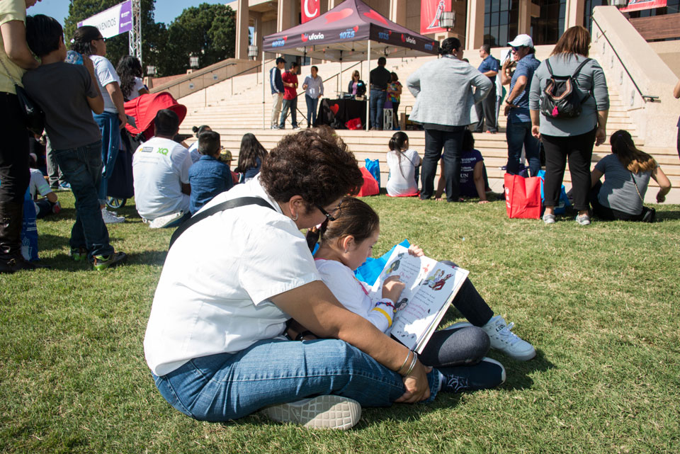 Mother and daughter read during Feria de Educación.