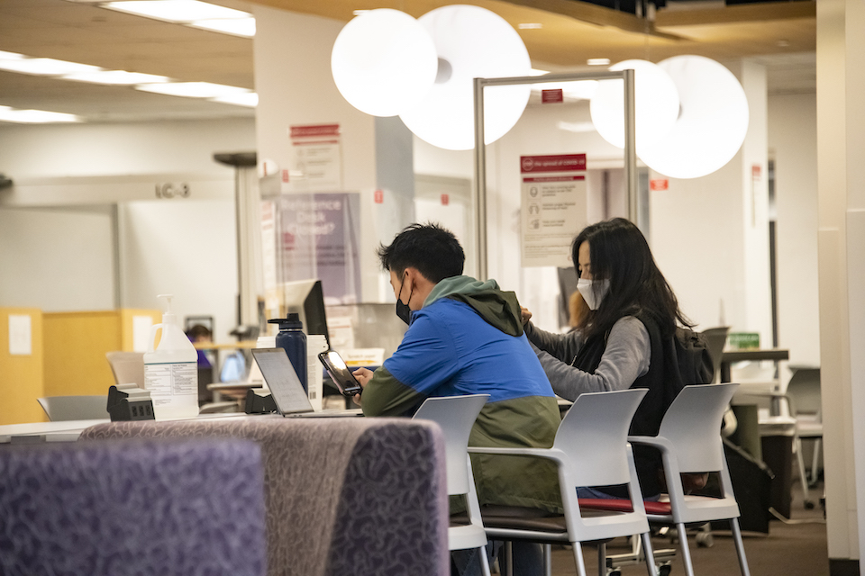 Students sit at a library table studying
