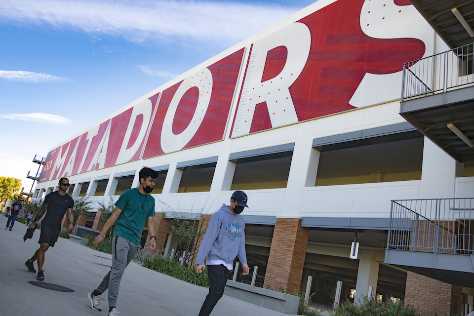 Students walk by parking structure with MATADORS painted on the side