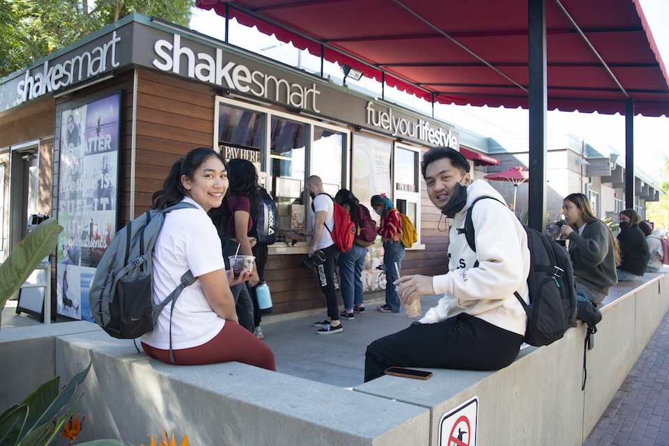 Students sitting on wall outside Shake Smart on campus