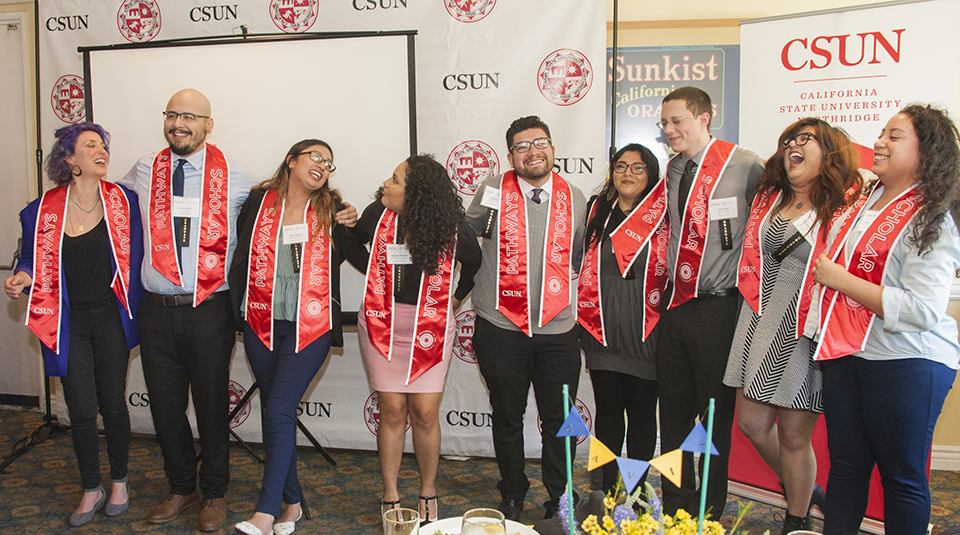 Eight HSI students laugh as they arrange themselves for a group photo.