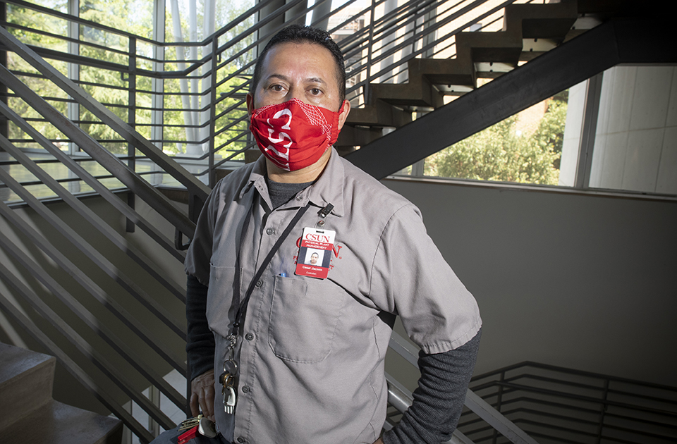 Portrait of Cesar Jacinto, custodian, in a stairwell, wearing a CSUN face mask.