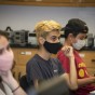 Students sitting at a desk wearing masks.