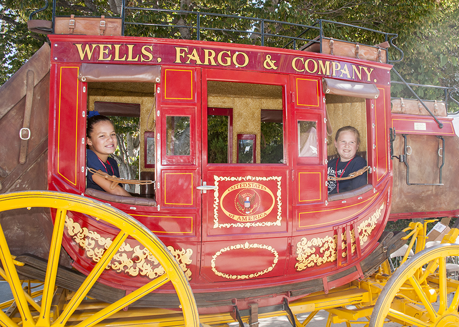 Children sit in a Wells Fargo stagecoach at Feria de Educación.
