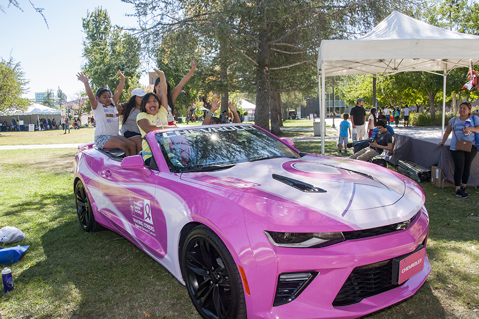 Children cruise in a pink American Cancer Society car.