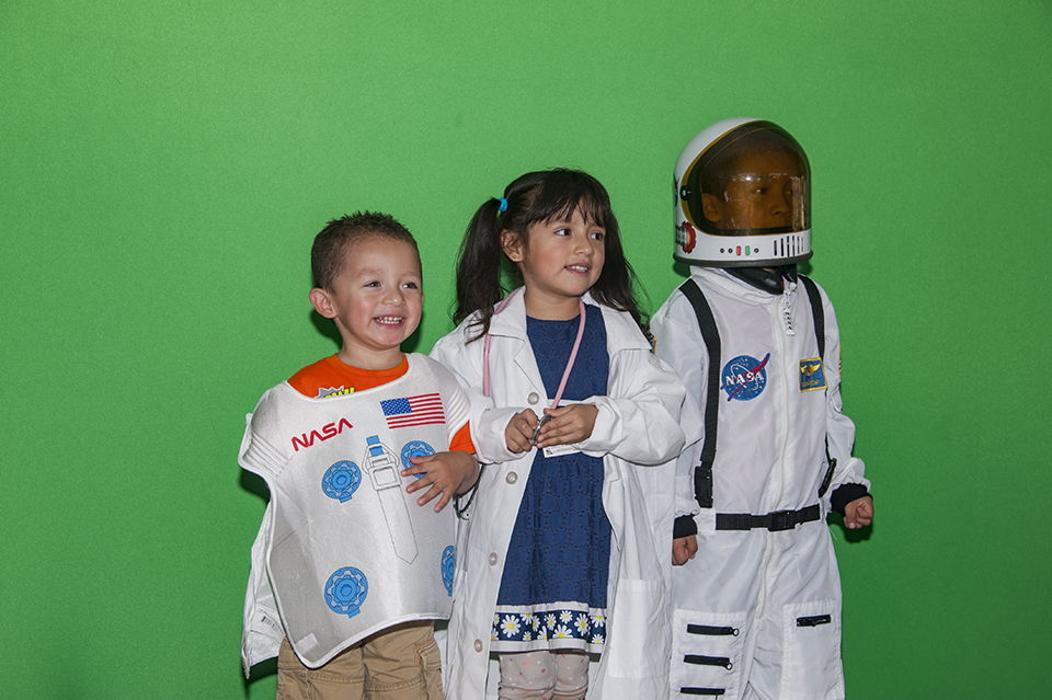 Students dress a doctor and two astronauts at Feria de Educación.