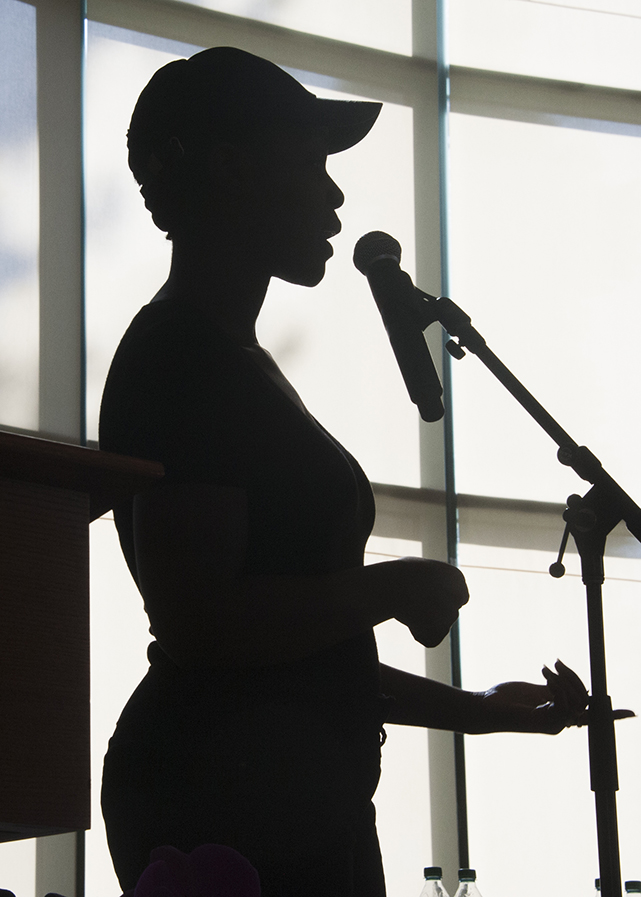 Funmilola Fagbamila is silhouetted at the microphone as she delivers a spoken-word piece.