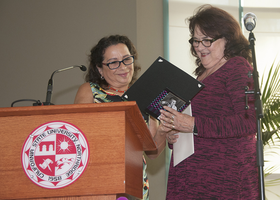 Judy Baca receives an award from Marta Lopez-Garza.