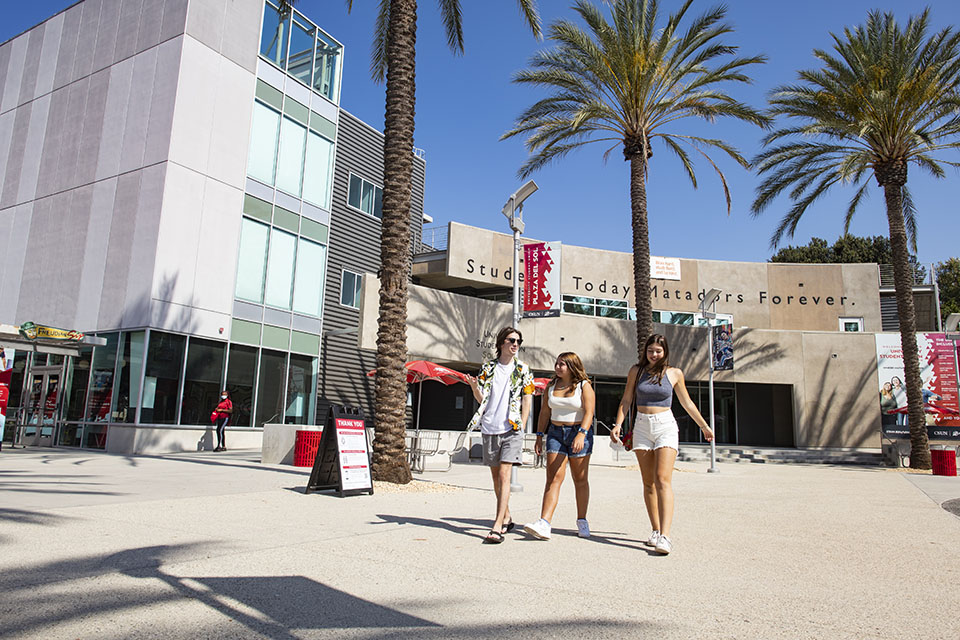 Three students walk on campus in front of the University Student Union at CSUN.