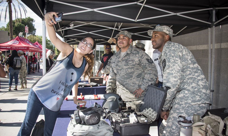 A woman taking a photo with two military personnel.