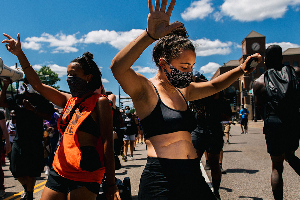 Two women in face masks dance during a protest in Minneapolis.