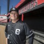 CSUN Baseball Head Coach Dave Serrano stands in front of the Matadors dugout at Matador Baseball Field.