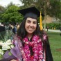 CSUN alumna Diana Naderi in cap and gown at her CSUN graduation, standing on campus and holding her diploma.