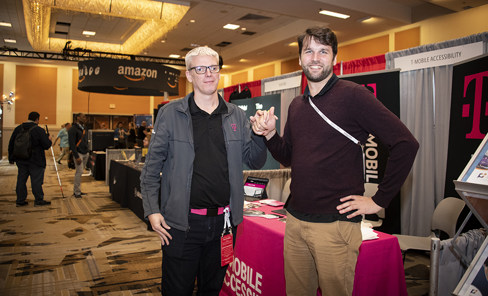 Keith Clarke (left) poses with interpreter Jay Slater Scancella in front of the T-Mobile booth in the exhibit hall