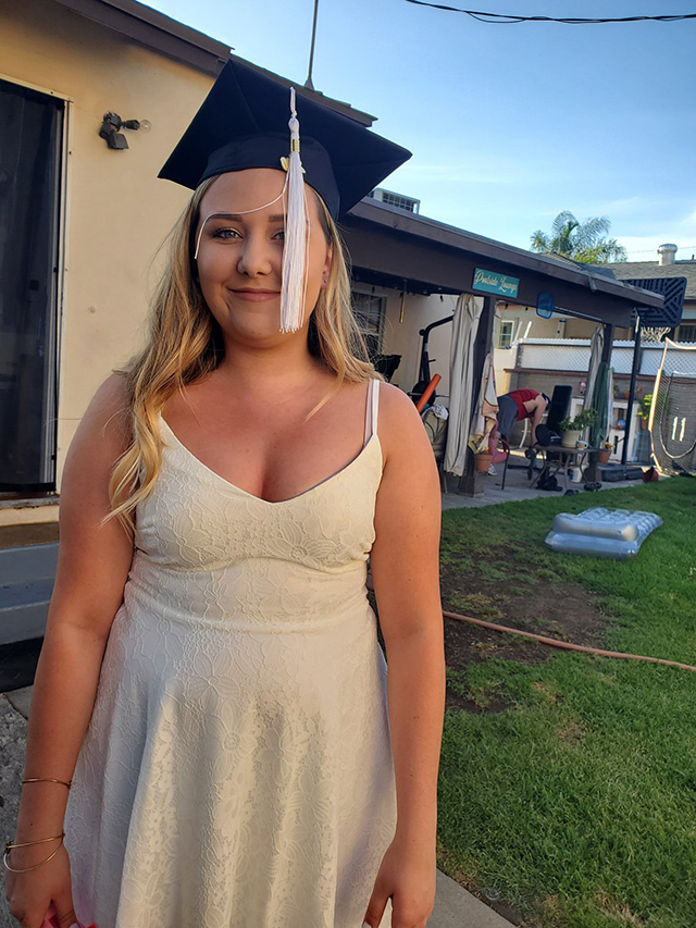 A CSUN student poses in her graduation cap at her home.