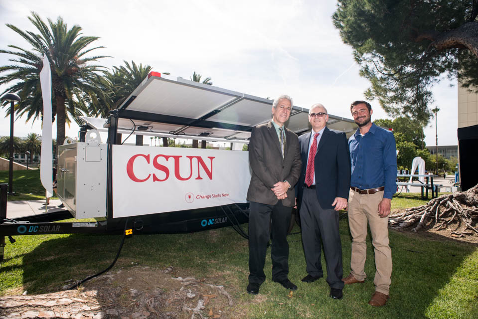 Sirotkin, Donahue and Eriksson stand next to large solar panel unit with CSUN branding on the side.