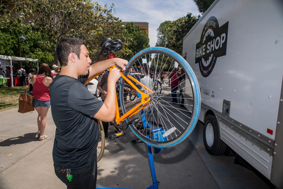 Student works on bike in front of truck with Matador Bike Shop logo.