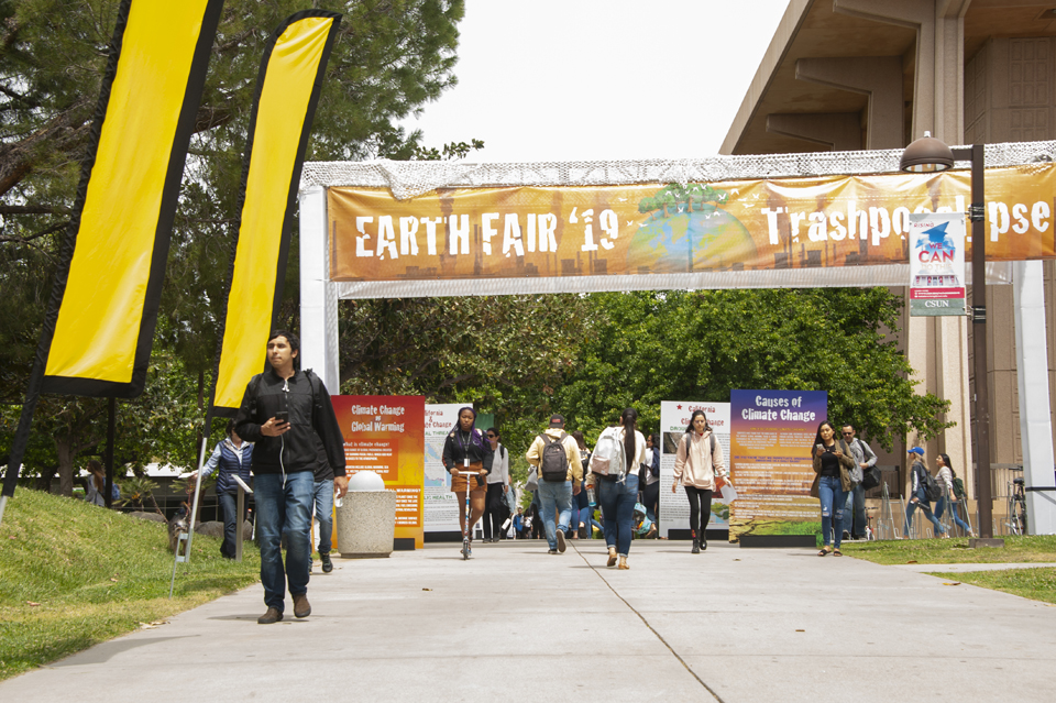 People walking under an Earth Fair banner.