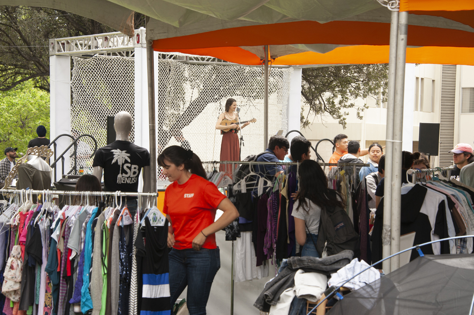 Women standing in tent with clothing racks.