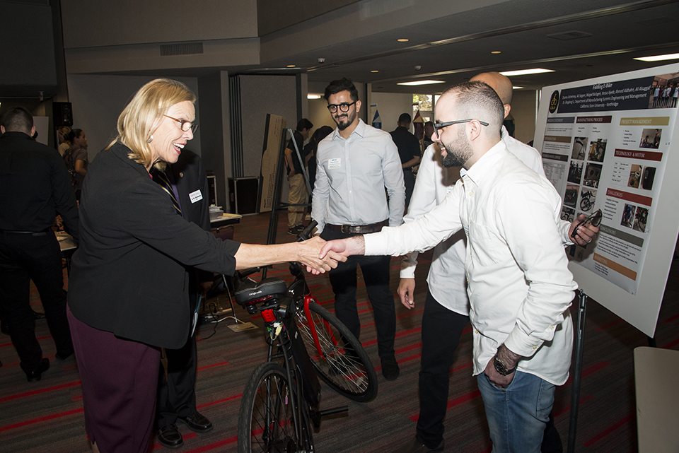 Engineering students present folding electrical bicycle to President Dianne F. Harrison.