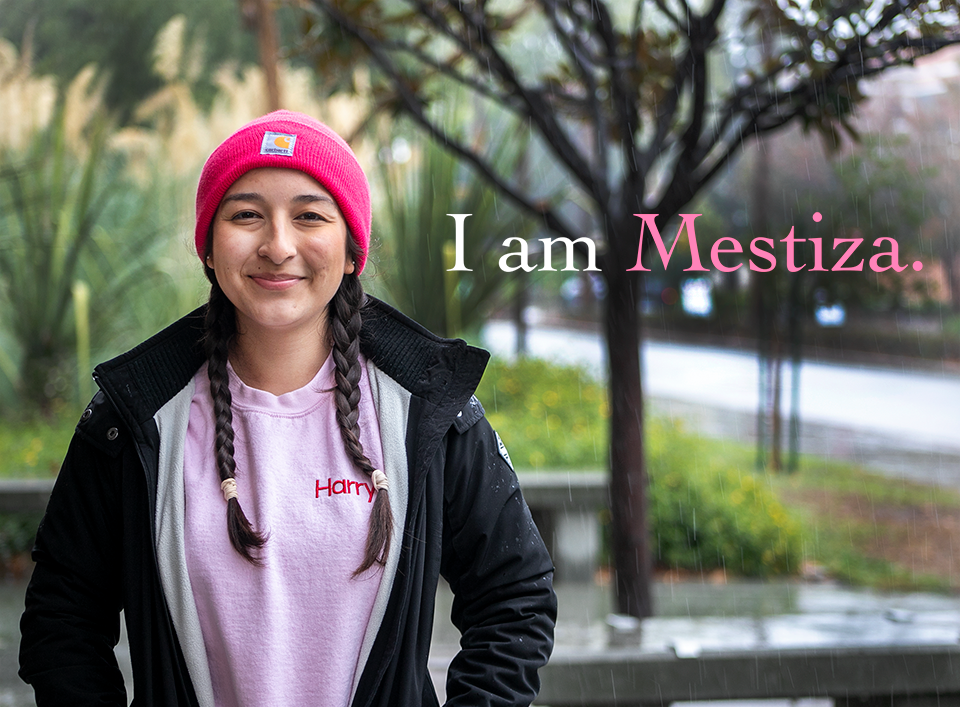 Portrait of Emma Perez standing outside wearing a pink beanie.