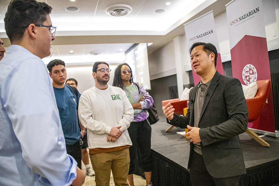Eric Chan stands talking with several students after his formal presentation.