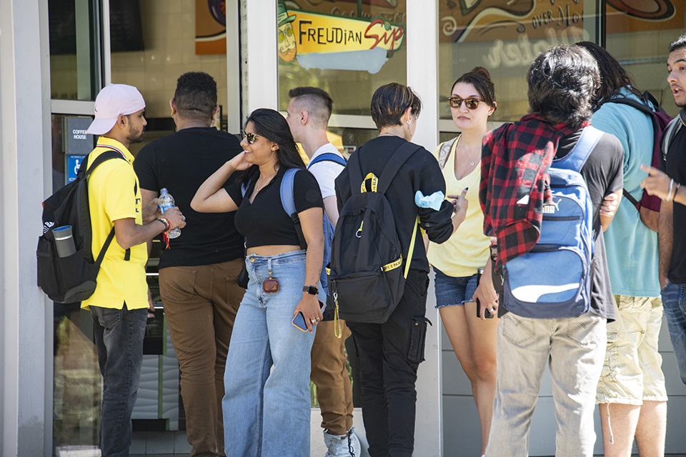 Students stand in line in front of coffee shop.