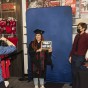 Student in cap and gown smiles for a photographer, has a chalkboard that says 