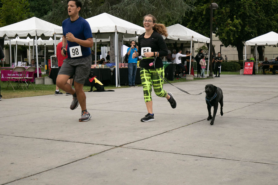 A woman runs with her dog in the CSUN 5K Matador Fun Run.