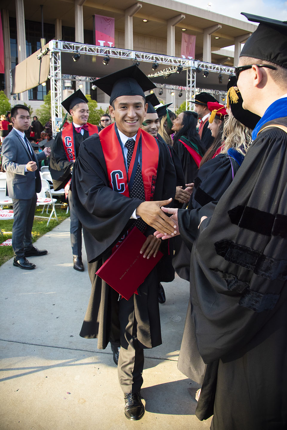 A line of CSUN graduates shakes hands with another line of CSUN graduates.