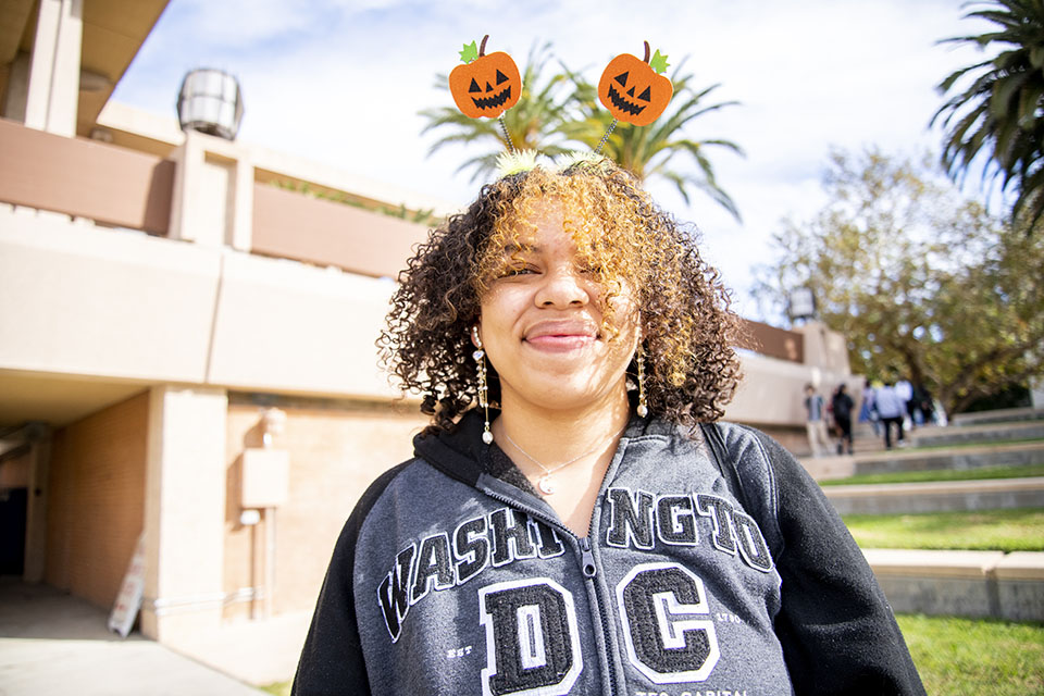 Smiling young woman wearing a headband with two pumpkins on it poses for the camera
