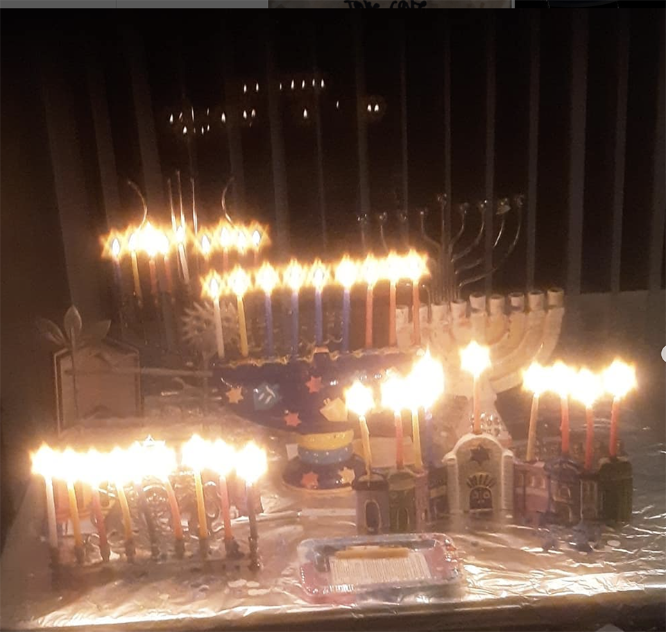 Four hanukkiot (Hanukkah menorahs), filled with candles, lit for the 8th day of Hanukkah.
