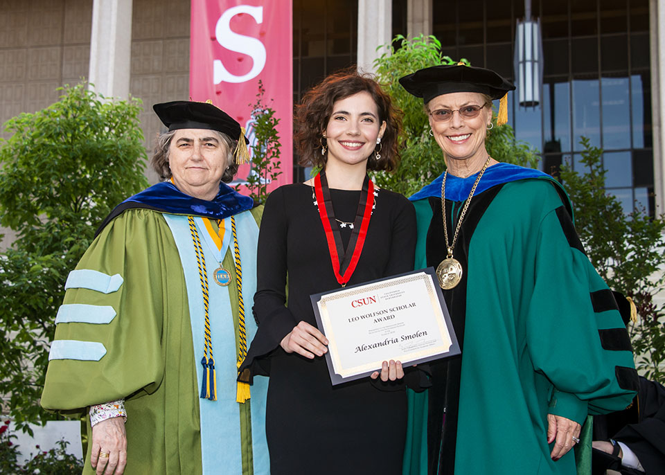 interim provost Stella Theodoulou and university president Dianne F. Harrison congratulate and award a medal and certificate to Wolfson scholar Alexandria Smolen during a graduation ceremony.
