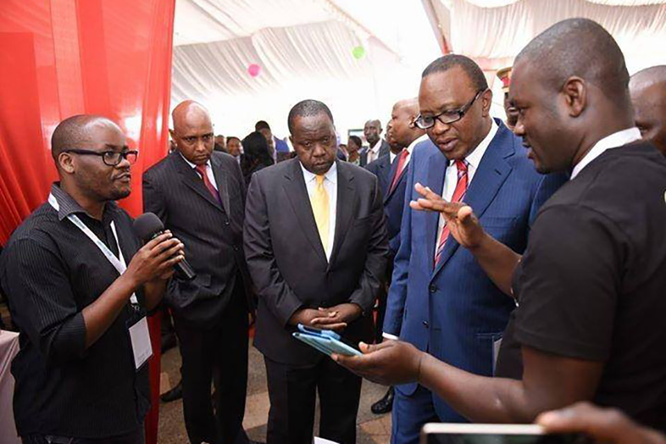CEO and co-founder of Deaf eLimu Plus, Hudson Asiema, demonstrating to Kenya President Uhuru Kenyatta the startup company's first Android app.