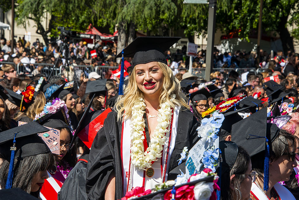 Honors English graduate Jessica Edwards stands to greet friends at CSUN commencement.