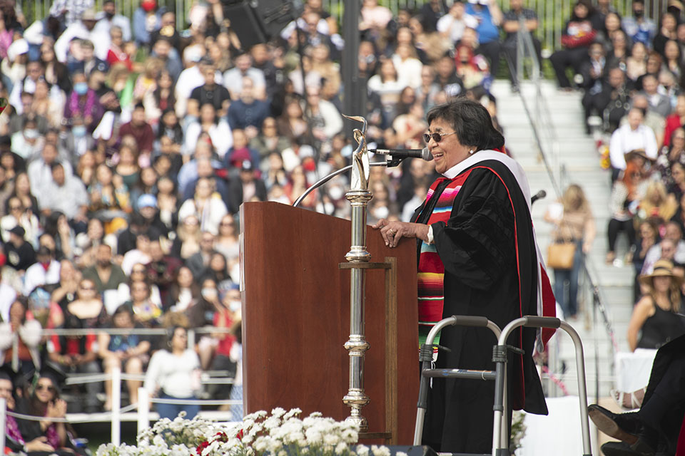 Honorary Doctorate recipient and CSUN alumna Irene Tovar stands at a podium, speaking to graduates at Commencement 2022.
